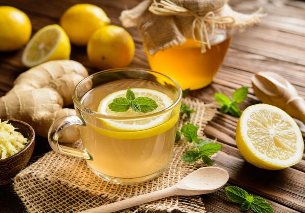 Cup of ginger root tea with lemon, honey and mint on a wooden background