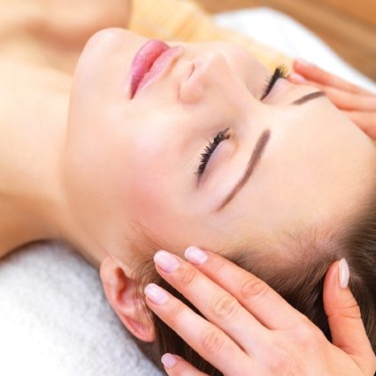 Head_massage Close up portrait of a young woman with eyes closed receiving facial massage