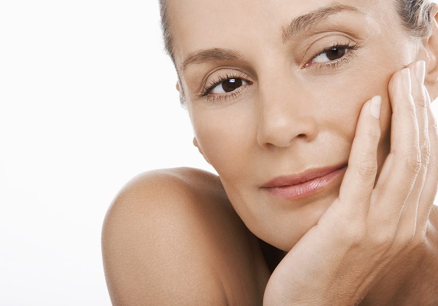 Closeup of relaxed middle aged woman with hand on chin over white background