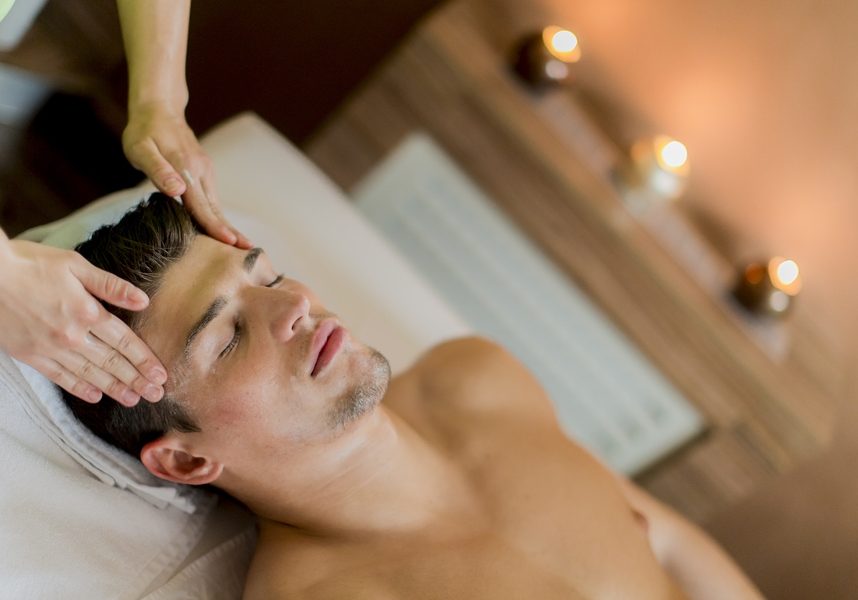 Handsome young man having facial massage in the spa