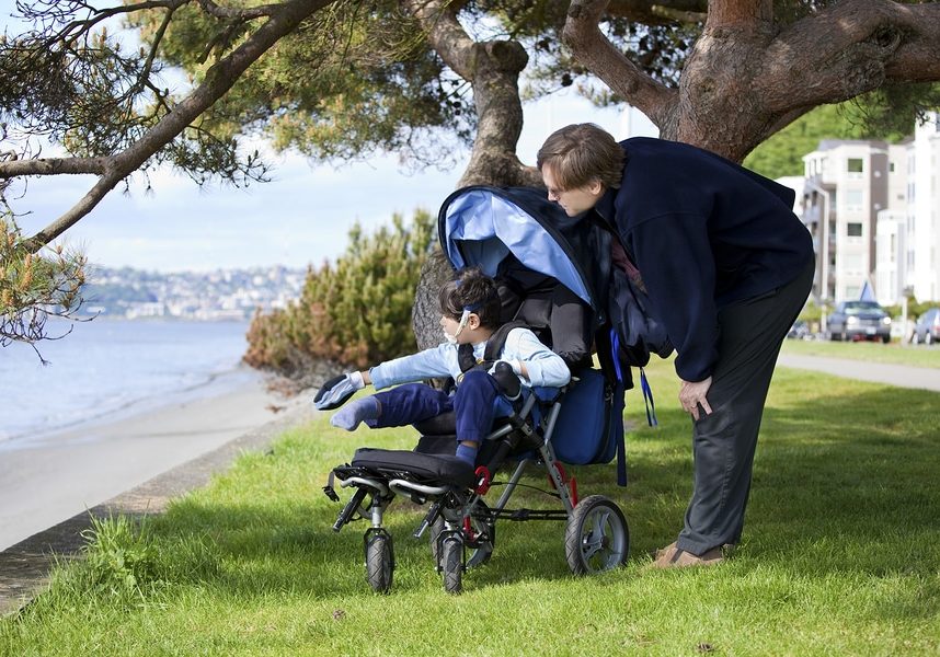 Father spending time with disabled son in wheelchair at the lake