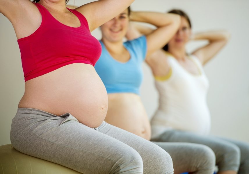 Young pregnant women doing exercise using a fitness ball