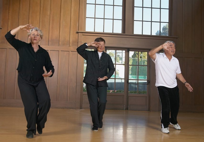 Three seniors practicing Tai Chi indoors