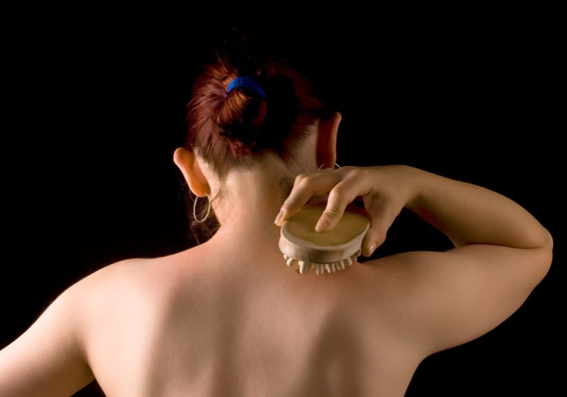 nude woman body while skin massage over black background